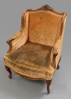une vieille chaise dont l'assise est recouverte d'un tissu marron et le dossier d'un tissu doré