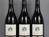 three bottles of wine are lined up on a table