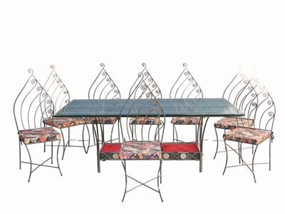 table de salle à manger en fer forgé et six chaises avec des coussins à motifs floraux