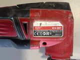 a red corded drill with a black handle on a white surface