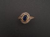 gros plan d'une bague en or avec une pierre bleue
