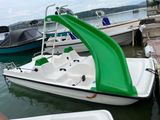 a green slide on the back of a boat in the water