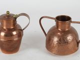 pair of antique copper jugs on a white background