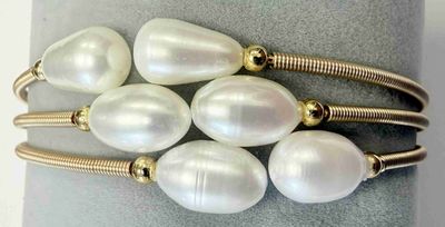 six perles blanches sont montées sur un bracelet plaqué or, sur un fond gris