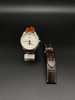 La montre est blanche et marron, avec un bracelet en cuir marron.