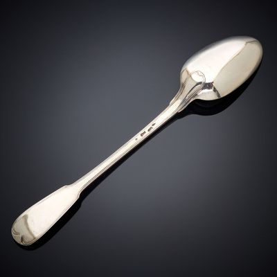 an antique silver spoon with a long handle on a black surface