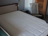 un lit avec un matelas et une chaise dans une chambre