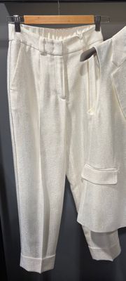 un pantalon de survêtement blanc suspendu à un cintre devant un mur noir