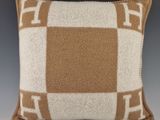un coussin en laine à carreaux marron et blancs sur fond gris