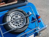 a small blue car with a large tire on the back of it