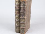 two old books sitting on top of each other on a white surface