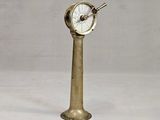 une horloge ancienne en laiton posée sur un socle, sur fond blanc