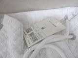 a white bag with a tag on it sitting on a bed