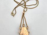 a gold necklace with fringes on a white background