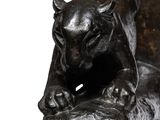 statue of a cat on a log with its paw resting on it ' s paw