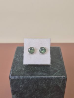 a pair of green tourmaline earrings sitting on top of a marble block