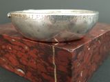 a silver bowl sitting on top of a red marble block