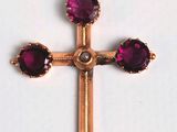 un gros plan d'une croix en or ornée de pierres violettes