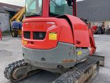 the back end of a red tractor parked in a parking lot