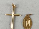 two small gold crosses and a gold medal on a white surface
