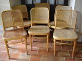 four wooden chairs sitting on a tile floor in front of a door