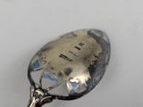 a silver spoon with writing on it on a white surface