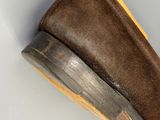 chaussons marron à semelles en caoutchouc posés sur une surface blanche