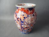 un vase orange et bleu posé sur une surface grise