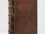 un vieux livre marron posé sur une table blanche