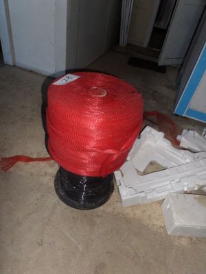 a red rope wrapped around a white object on the floor