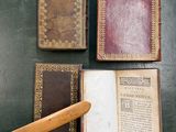 three old books and a wooden mallet on a table