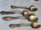 six silver spoons are lined up on a white table cloth