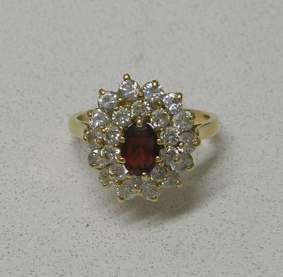 gros plan d'une bague avec une pierre rouge entourée de diamants blancs