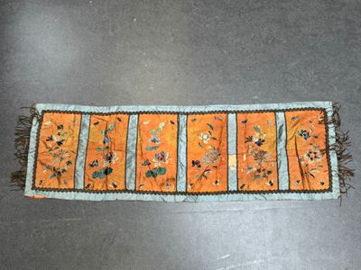 an orange table runner with flowers and birds on it