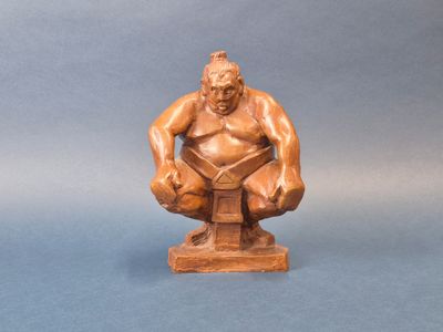 une image représentant une statue d'un homme assis sur un bloc de bois