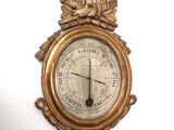 a gold clock on a white wall with a bird on it