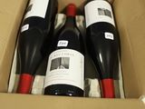 trois bouteilles de vin dans un carton avec une étiquette de prix