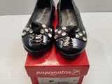 une paire de chaussures noires pour femme ornées de nœuds, posée sur une boîte rouge