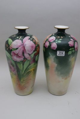 two vases with flowers painted on them sitting on a table