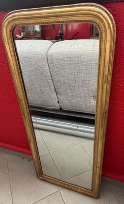 gold framed mirror on the floor in front of a red wall
