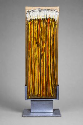 sculpture représentant un bouquet de bâtonnets jaunes et orange posés sur un socle métallique
