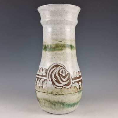 a white vase with a green and brown design on it