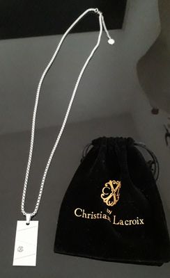 Collier Christian Lacroix posé sur une table, accompagné d'un sac en velours noir