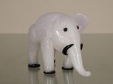 une petite figurine d'éléphant blanche posée sur une surface brillante
