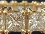 a close up of a gold ring with five princess cut diamonds