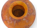 an orange vase that is sitting on a white surface
