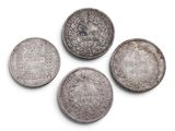 four silver coins are arranged on a white surface