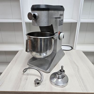 a mixer sitting on a table with a metal bowl on it