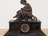 une statue de femme assise au sommet d'une horloge