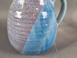 a blue and white pitcher sitting on a table next to a cup